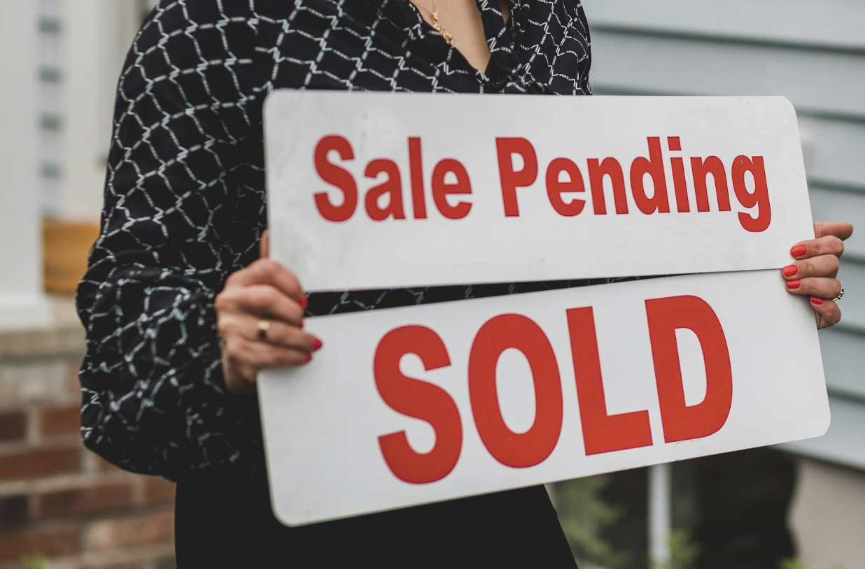 Female Real Estate Agent Holding Sale Pending and Sold Signs